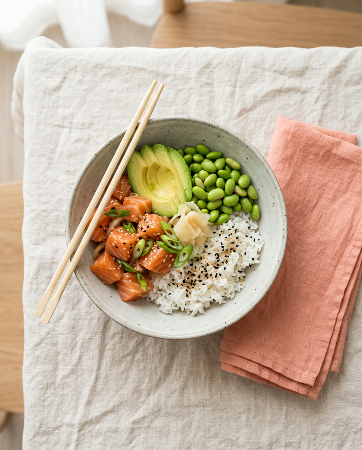A bowl of salmon poke on a linen tablecloth, seen from above